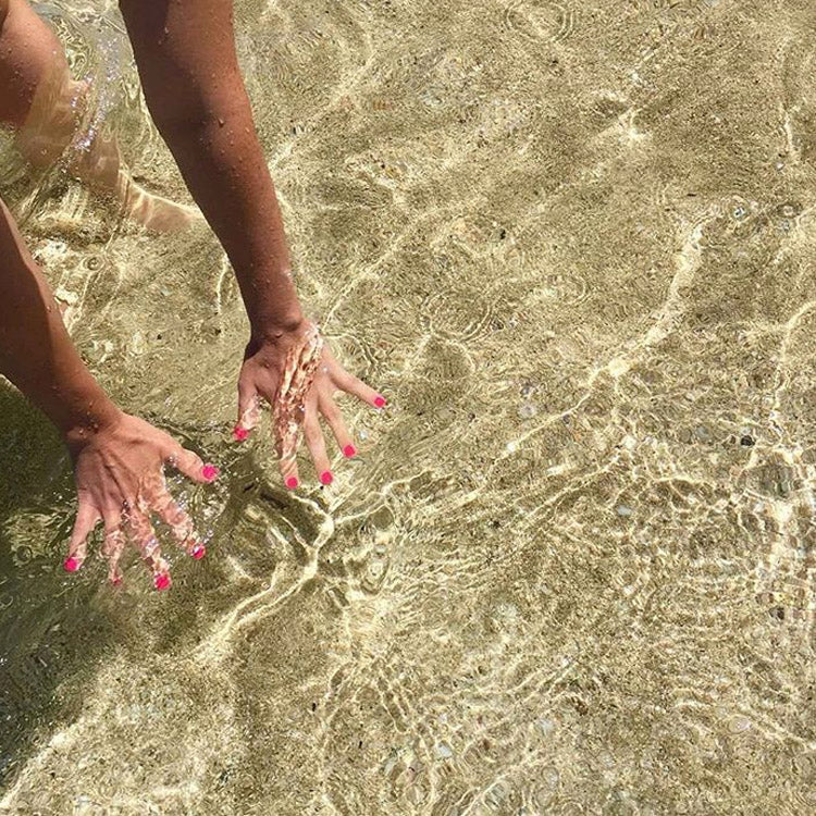 Lifestyle shot of model's hands wearing Beach Toes Sunday Session Fluro Pink Nail Polish